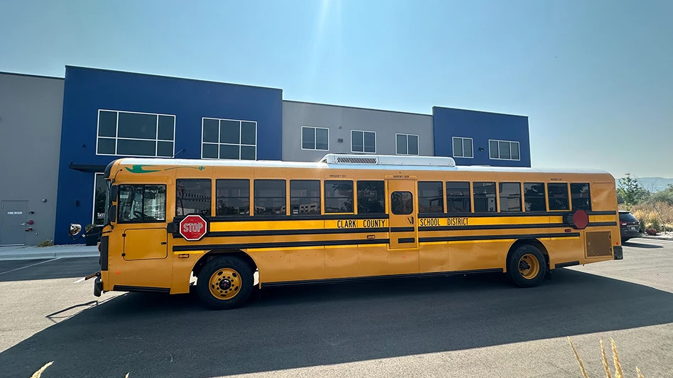 An electric school bus outside a school