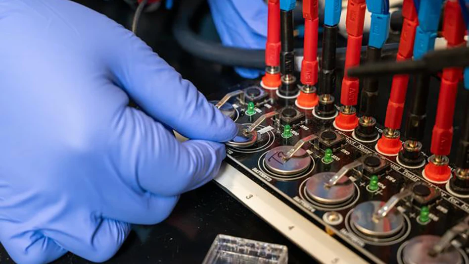 A gloved hand tests a battery