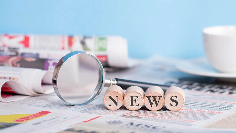A magnifying glass and round wooden letters spelling "news" sit on a newspaper