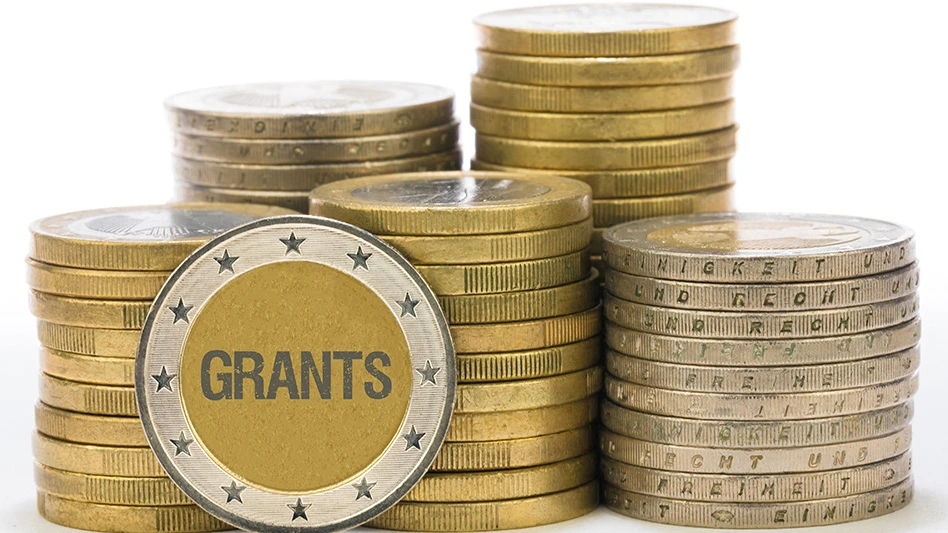 A stack of gold coins with one coin facing outward and the word "grants" on it