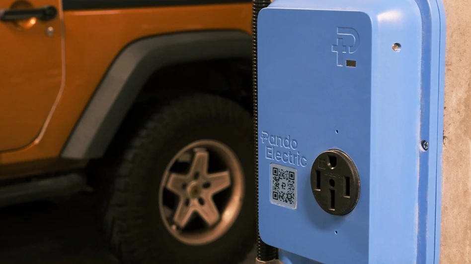 A blue electrical outlet mounted on a wall with a car in the background