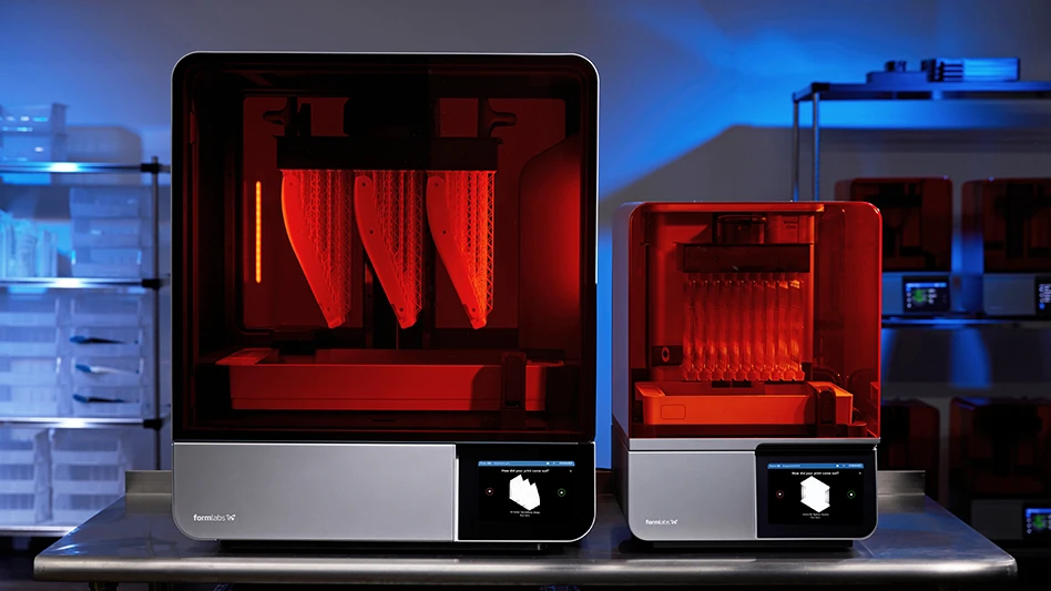 Two orange 3D printers sit on a shelf