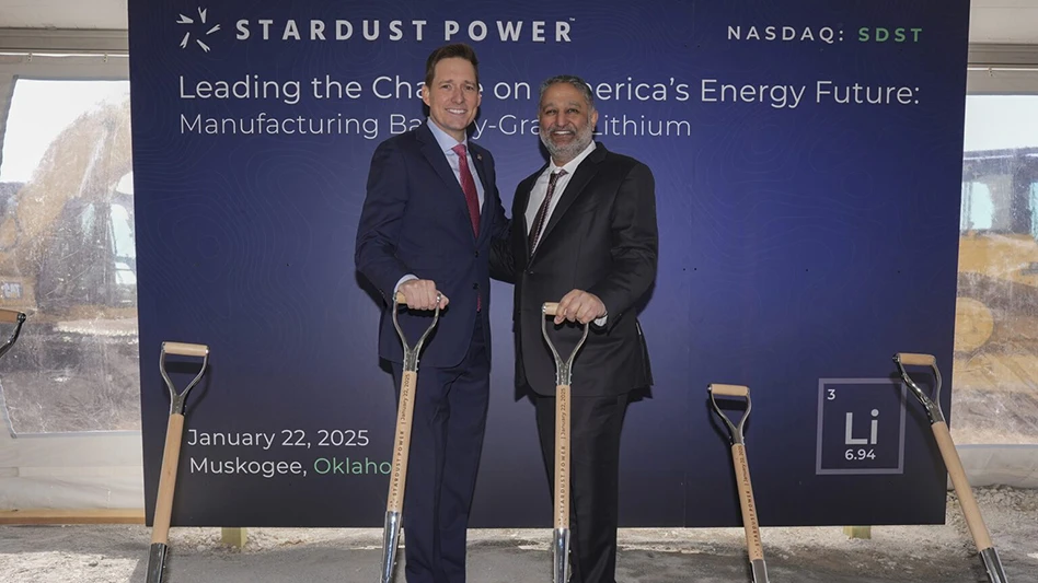 Two people hold shovels in front of a banner