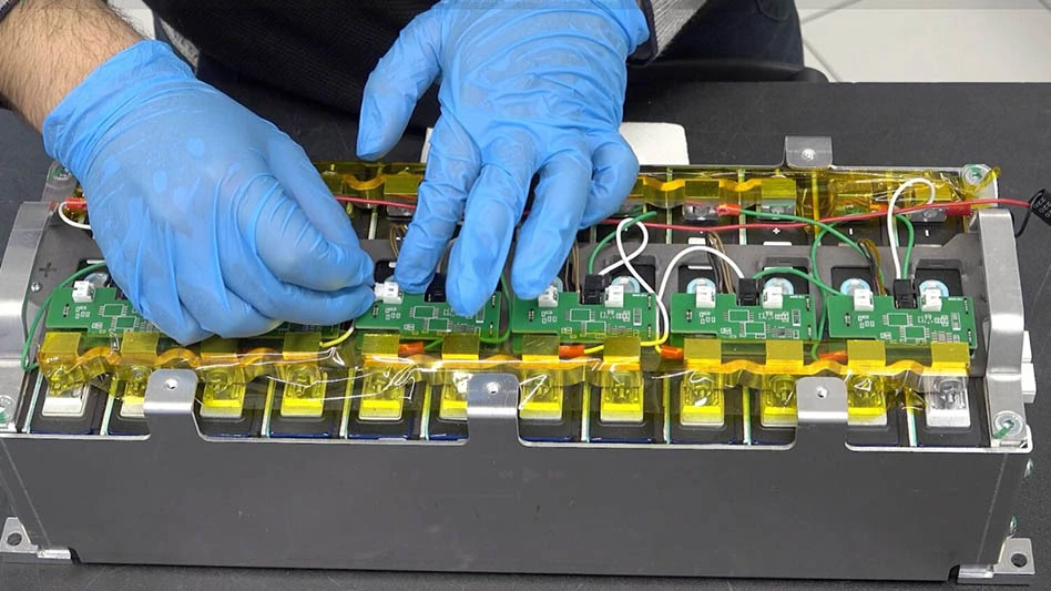 A pair of hands in blue gloves working on a battery