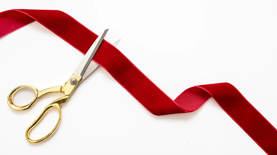 Gold scissors cutting a red ribbon