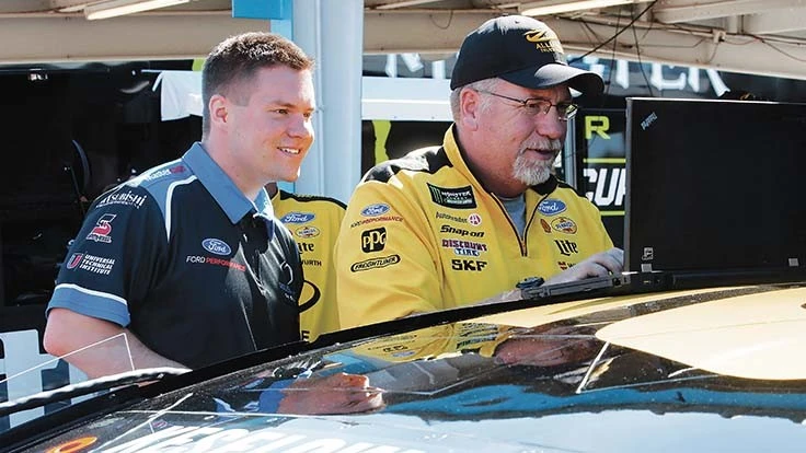 Technician Mike Luckhard and NASCAR Tech graduate Adam McMaster fine-tune a car for NASCAR Champion Brad Keselowski.